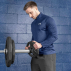 Male athlete adding 5kg plate to barbell