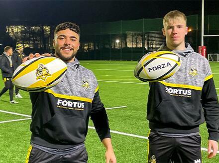 2 rugby players holding rugby balls